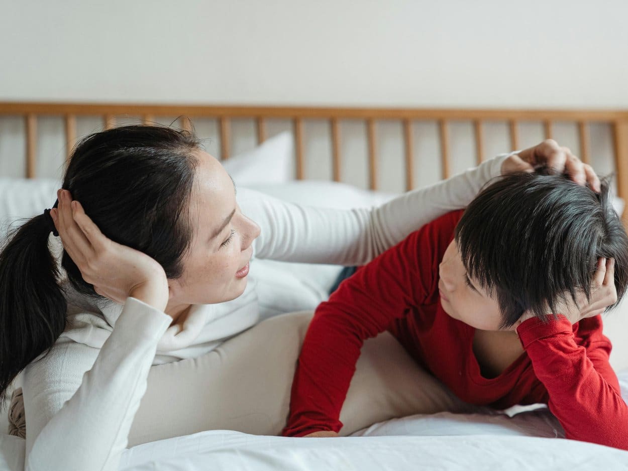 A mother and her son lying on a bed together, laughing